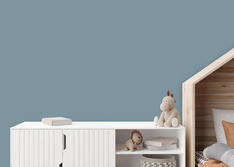 Blau-graue Wandfarbe in einem hellen, organisierten Kinderzimmer mit weißem Sideboard und einem Hausbett aus Holz.