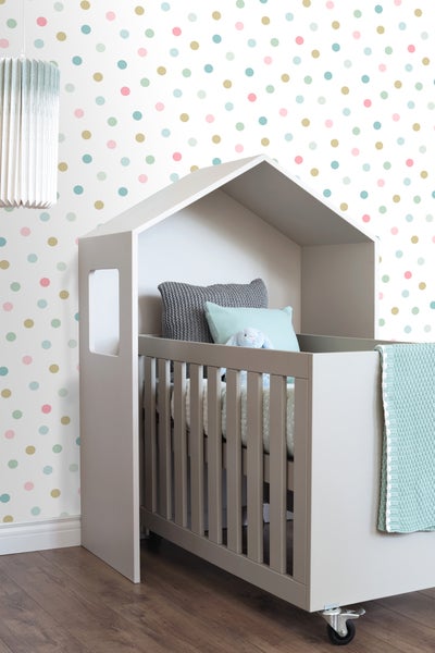 Graues Kinderbett mit Hausdach und Rollen mit Kissen und Kuscheltier