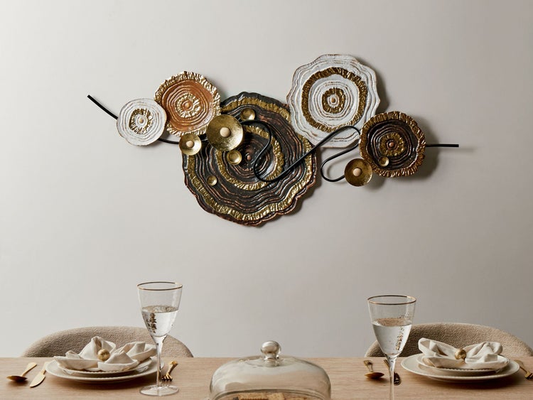 Wanddekoration aus Metall in Form von Baumscheiben über einem Esstisch