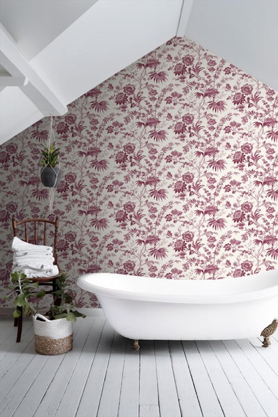 Tapete mit Blumenmuster in einem hellen Badezimmer mit freistehender Badewanne, Holzstuhl und weißem Dielenboden.