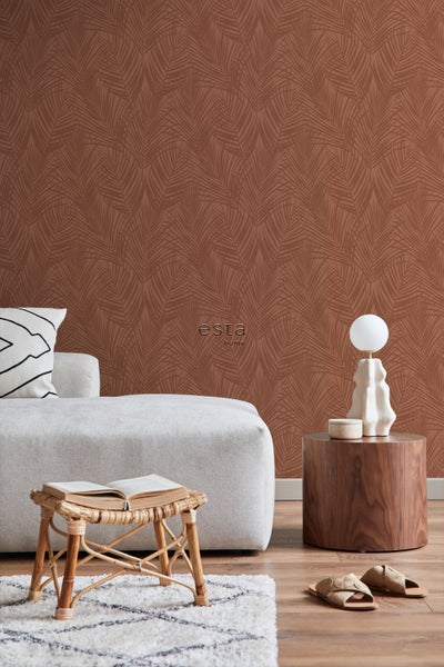 Dekorative Wohnraumszene mit einer Wandtapete mit Blattmuster, einem Sofa, einem Beistelltisch und einer Lampe.