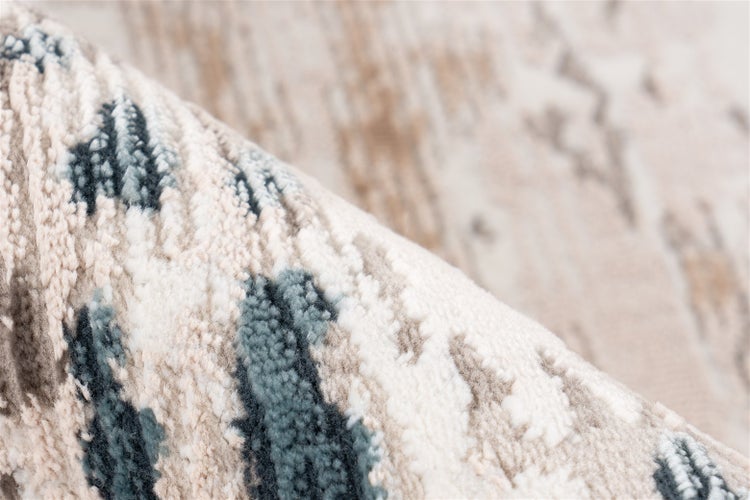 Nahaufnahme eines strukturierten Teppichs in Blau, Beige und Grau mit abstraktem Muster.