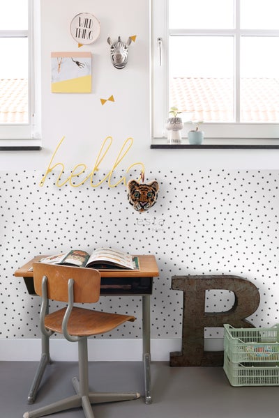 Kinderzimmer mit Schreibtisch, Stuhl, Dekoration und gepunkteter Tapete für eine freundliche Atmosphäre