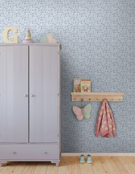 Vliestapete mit feinem blau-weißem Blumenmuster in einem hellen Kinderzimmer mit fliederfarbenem Kleiderschrank und Holzregal.