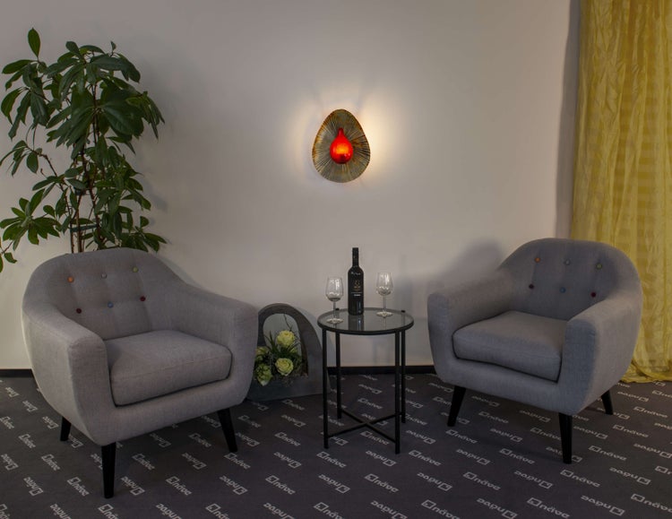 Wohnzimmer-Szene mit zwei Sesseln, Beistelltisch mit Wein und Gläsern sowie dekorativer Wandleuchte