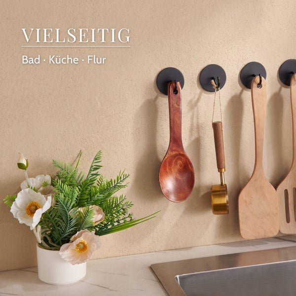 Mehrere an der Wand montierte Haken in einer Küche mit hängenden hölzernen Küchenutensilien und einer Blumenvase auf der Arbeitsplatte.