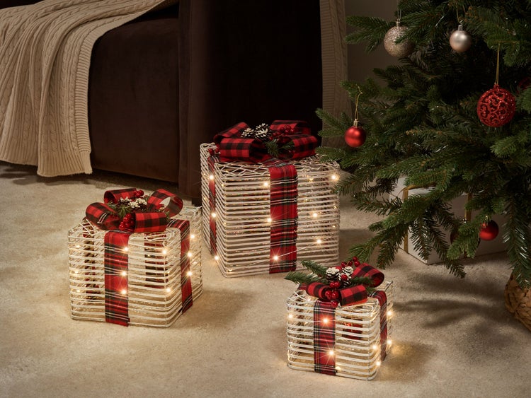 Dekorative Geschenkpakete mit Schleife und Beleuchtung neben einem Weihnachtsbaum