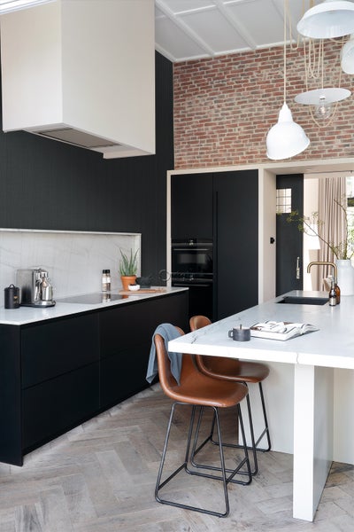 Helle und moderne Küche mit Kücheninsel, Barhockern und Backsteinwand