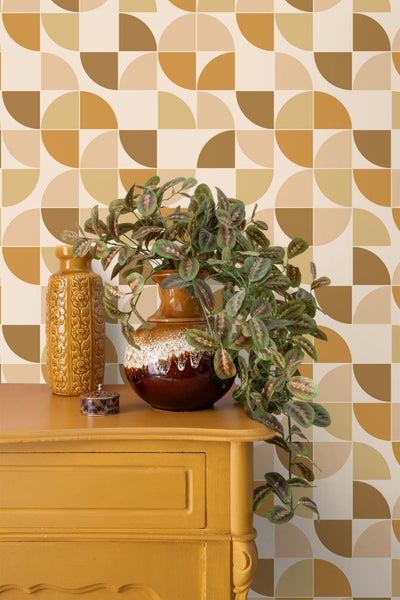 Retro-Tapete mit geometrischem Muster aus Halbkreisen hinter einer Kommode mit dekorativen Vasen und einer rankenden Zimmerpflanze.