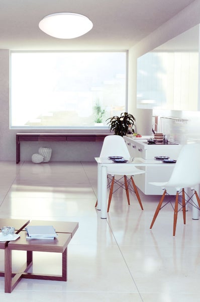 Helle Küche mit weißen Schränken, Dunstabzugshaube und Spüle unter einem Fenster.