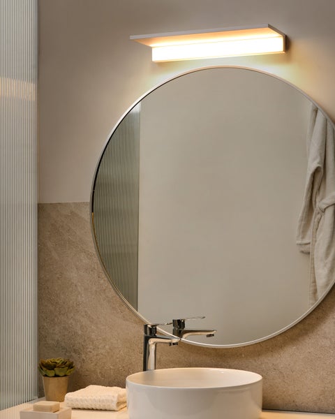 Modernes Badezimmer mit rundem Spiegel, Aufsatzwaschbecken und Wandleuchte