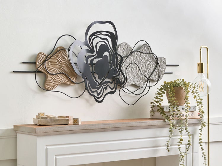 Dekorative Wandgestaltung mit abstrakten Formen und Metallakzenten über einem Kaminsims