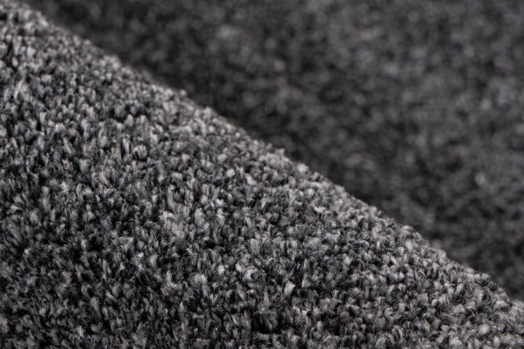 Nahaufnahme eines grauen Hochflor-Teppichs mit weicher, dichter Textur.