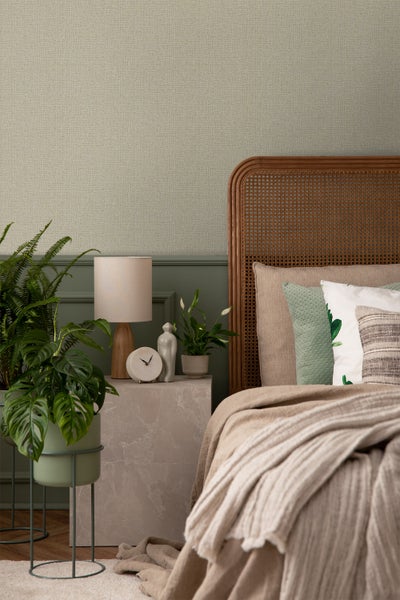 Gemütliches Schlafzimmer mit Rattankopfende, Nachttisch und Zimmerpflanzen