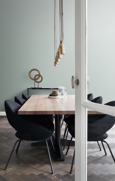 Esstisch mit Stühlen, Hängelampe und Dekoration in einem hellen Raum.