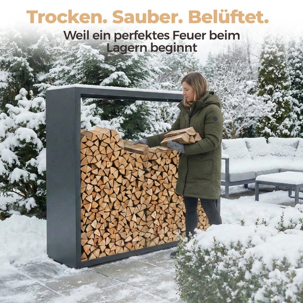 Frau lagert Brennholz in einem modernen Brennholzregal im winterlichen Garten.