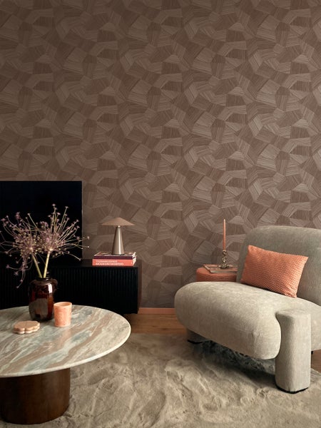 Wohnzimmer mit brauner Tapete mit geometrischem Muster, Sessel und Tisch