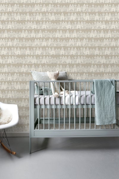 Kinderzimmer mit beiger Tapete mit Häusern, Babybett und Schaukelstuhl.