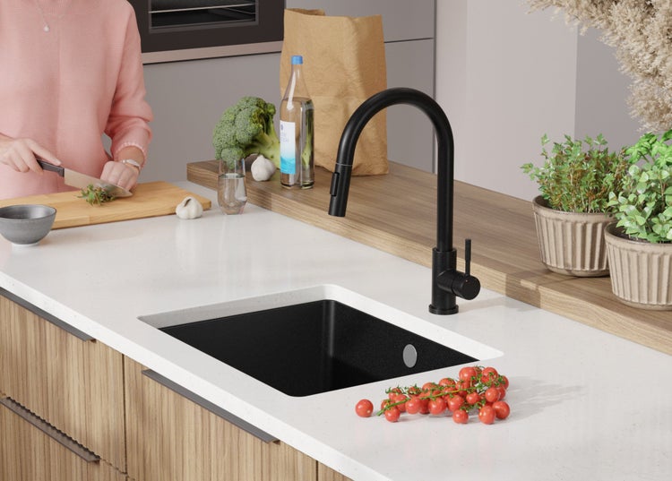 Küchenszene mit schwarzem Spülbecken, Armatur und Lebensmitteln auf der Arbeitsfläche.