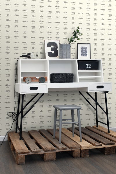 Szene mit Schreibtisch, Stuhl und Dekorationsgegenständen vor einer Wand mit Tapete mit Knotenmuster.