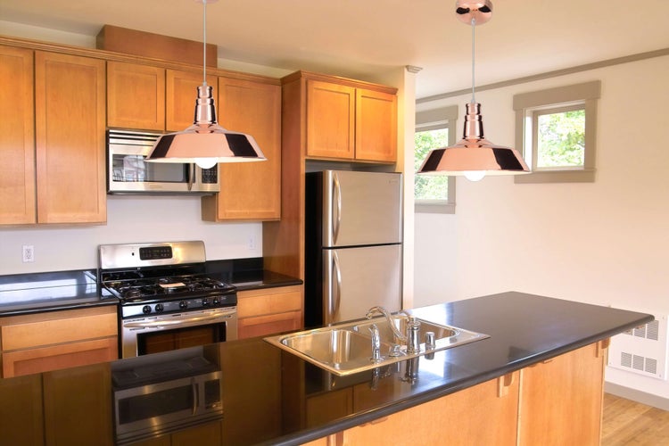 Küchenszene mit Einbauschränken, Edelstahlgeräten und zwei Pendelleuchten