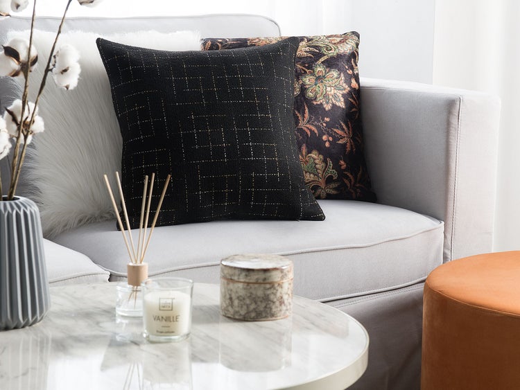 Dekorative Kissen auf einem Sofa mit Beistelltisch mit Duftkerze, Diffusor und Dose