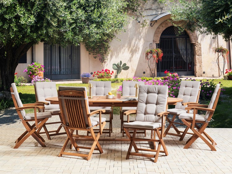 Gartenszene mit ovalem Holztisch und acht Holzstühlen mit Polsterauflagen