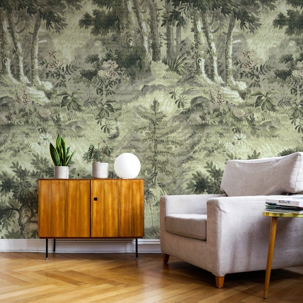 Vlies-Fototapete mit Wald- und Dschungelmotiv in einem Wohnzimmer mit Holzkommode und hellem Sessel.