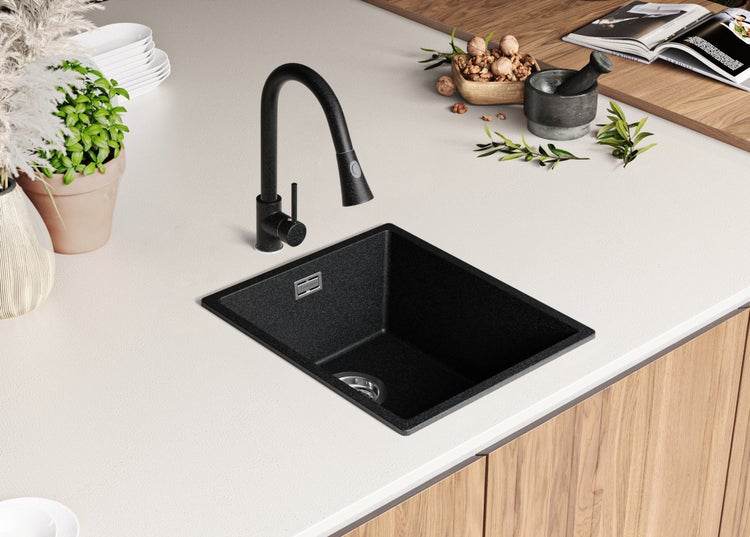 Schwarzes Küchenspülbecken mit Wasserhahn auf einer Arbeitsplatte.