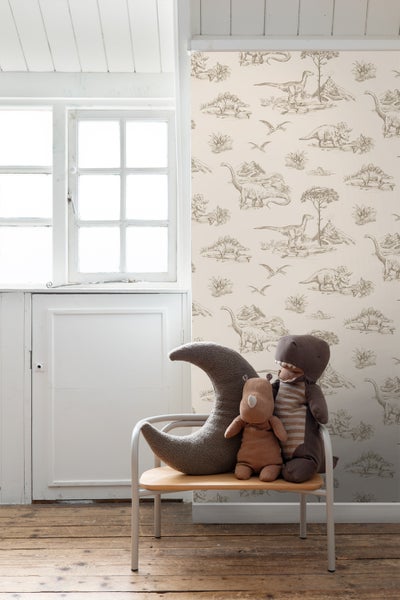 Kinderzimmer mit Dinosaurier-Tapete und Spielzeug auf einem Stuhl