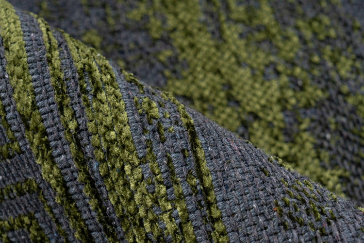 Nahaufnahme eines gewebten Teppichs mit strukturierter Oberfläche in Anthrazit und Grün.