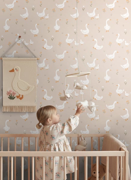 Zimmer mit Tapete mit Gänsemotiv, Mobile und Kind im Kinderbett.