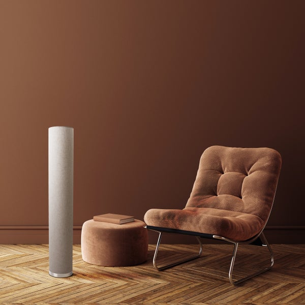 Einrichtungsbeispiel mit Sessel, Hocker und Stehleuchte vor einer braunen Wand