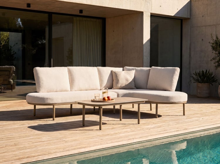 Modernes L-förmiges Outdoor-Loungesofa mit hellen Polstern und passendem Couchtisch auf einer Holzterrasse neben einem Pool.