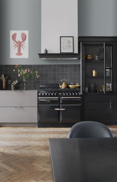 Küchenszene mit schwarzem Herd, Küchenschrank und Accessoires auf einer Holzoberfläche
