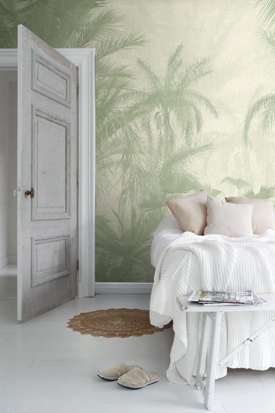 Schlafzimmer mit Bett, Beistelltisch und Tapete mit Palmenmotiv