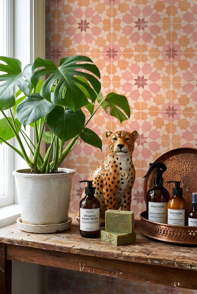 Wandfliesen mit geometrischem Muster hinter einer Monstera Pflanze, Leopardenfigur und Pflegeprodukten auf einem rustikalen Holztisch.