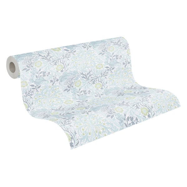 Dekorative Tapete mit floralem Muster hinter einer Kommode mit Topfpflanze und Uhr