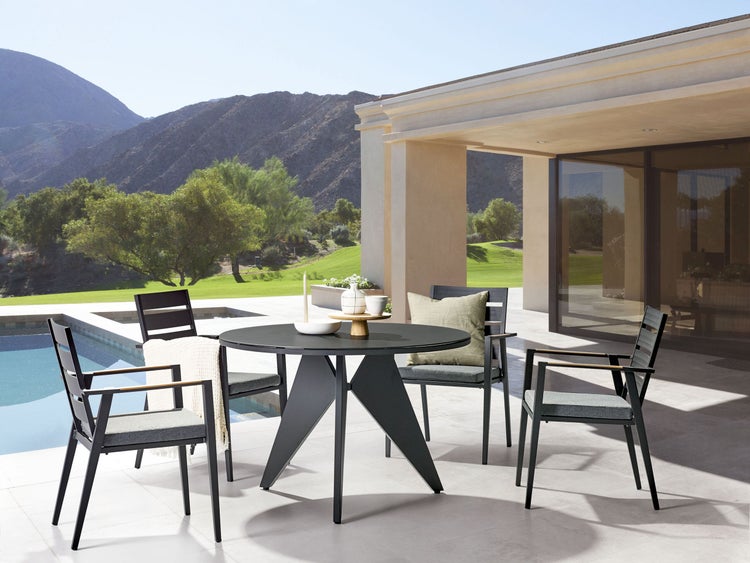 Gartensitzgruppe mit rundem Tisch und Stühlen auf einer Terrasse mit Pool und Bergblick