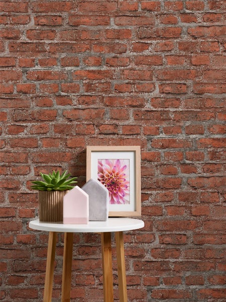 Schreibtisch mit Schreibtischlampe, Bürostuhl und Dekoration vor einer Ziegelwand