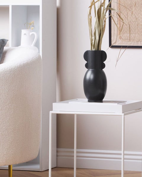 Dekorative schwarze Vase auf weißem Beistelltisch