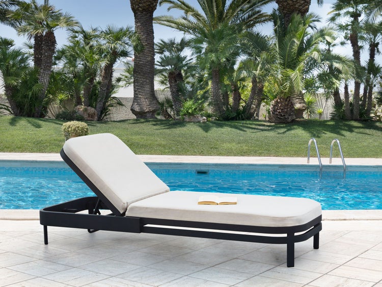 Liegestuhl mit Polsterauflage neben Pool und Garten