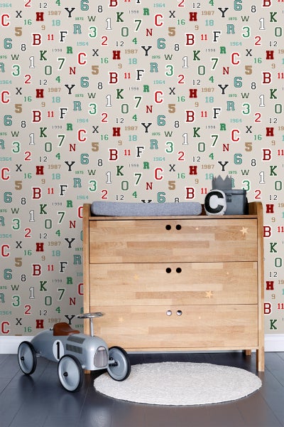 Kinderzimmer mit Wickelkommode, Spielzeugauto und Teppich vor einer gemusterten Tapete