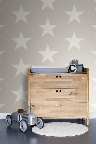 Holzkommode mit Wickelauflage, Spielzeugauto und Teppich vor einer Wand mit Sternenmuster