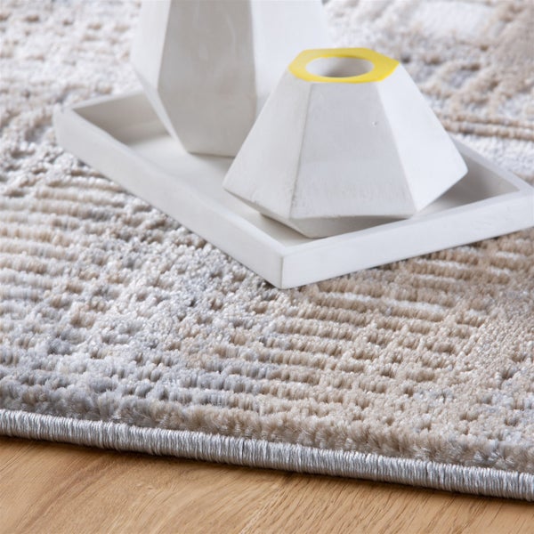 Strukturierter Teppich mit geometrischem Muster und eingefasster Kante auf Holzfußboden mit dekorativem Tablett.