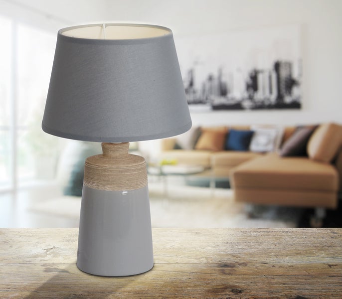 Tischleuchte mit Stoffschirm und Keramikfuß auf Holztisch