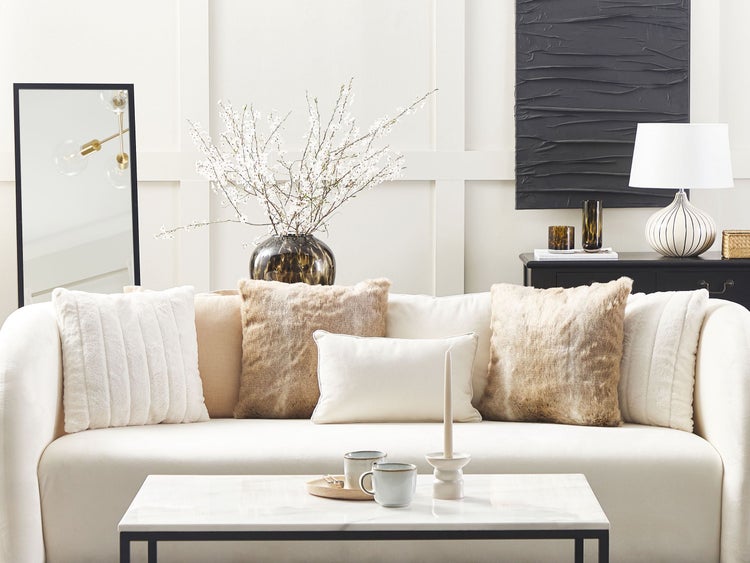 Wohnzimmer mit weißem Sofa, Kissen und Couchtisch