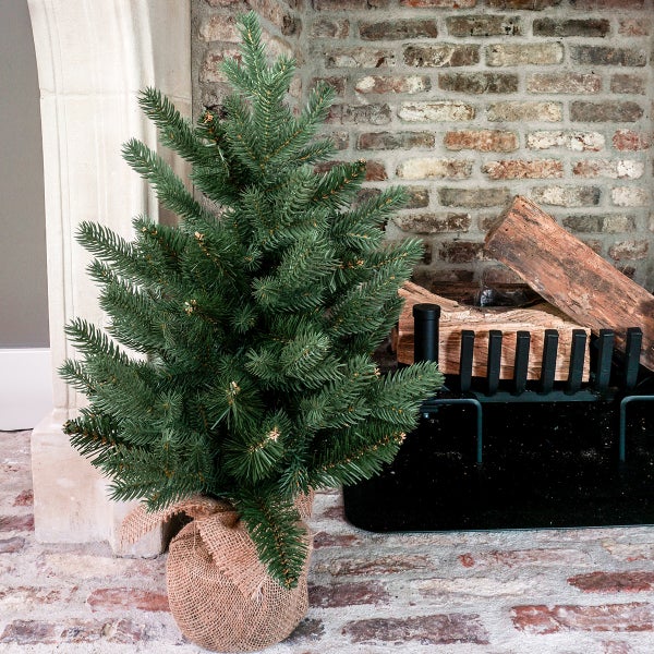 Künstlicher Weihnachtsbaum im Jutesack vor Kamin