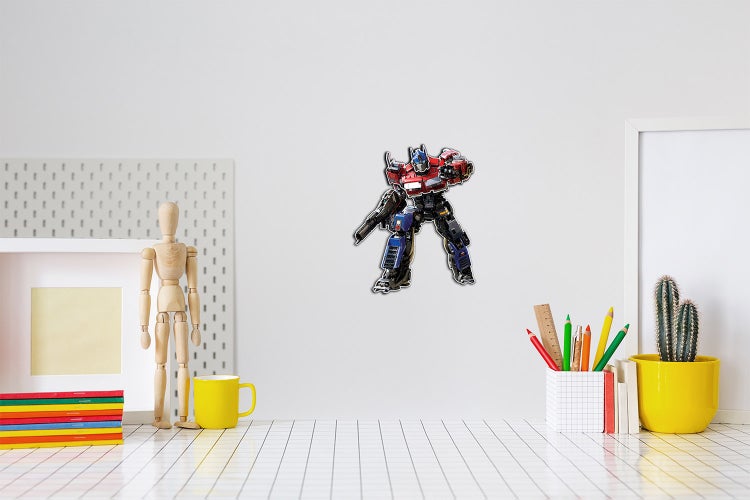 Wandsticker Transformers Optimus Prime an der Wand über einem hellen, organisierten Schreibtisch mit Holzmodell und Schreibutensilien.