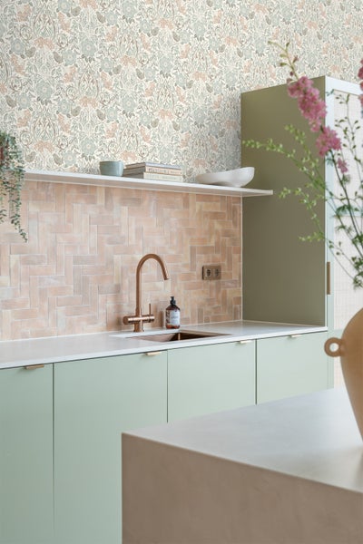 Küchenszene mit floraler Tapete und hellgrünen Küchenschränken